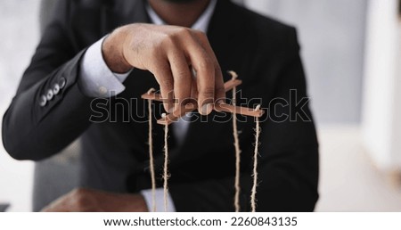 Marionette Manipulation With Hand Holding Puppet Strings Royalty-Free Stock Photo #2260843135