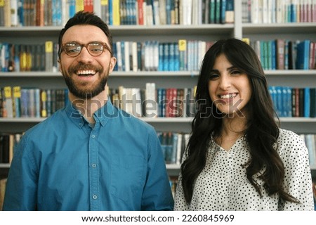 Friends with glad and delighted expression spend productive day in library showing sincere emotions. Man and woman enjoy spending day in library