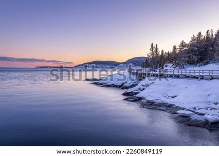 in Tadoussac the footbridge of the Pointe de l'Islet allows you to see whales. during a sunset in winter. Royalty-Free Stock Photo #2260849119