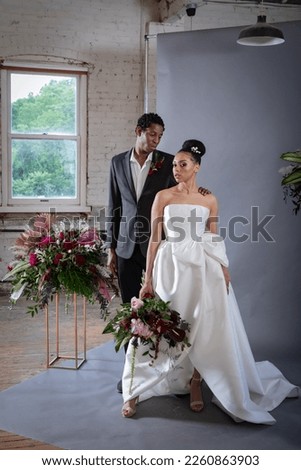 Beautiful wedding couple photo shoot with large peony and anthurium bouquet in-front of grey backdrop in old loft space
