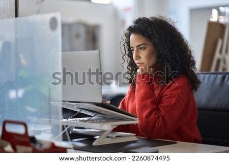 Young latin professional business woman office worker analyst sitting at desk working on laptop thinking on project plan, analyzing marketing or financial data online, watching elearning webinar. Royalty-Free Stock Photo #2260874495