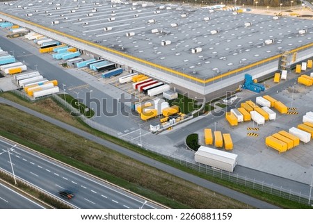 Many large semi-trailers are parked next to the logistics warehouse, waiting to be loaded for transport around the country. Royalty-Free Stock Photo #2260881159