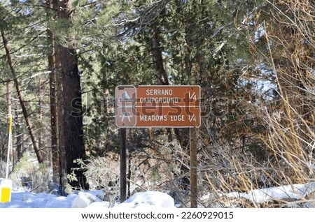 The 1 fourth mile Serrano Campground and Meadows Edge sign on the side of the road in Big Bear Lake, California.