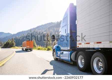 Industrial long hauler big rigs semi truck tractors with high cabs for truck driver rest transporting commercial cargo in different semi trailers driving in convoy on the highway road at sunny day Royalty-Free Stock Photo #2260932177