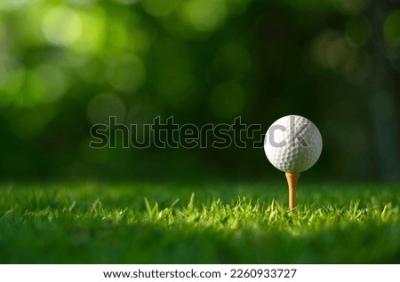 Close-up golf ball on tee with blur green bokeh background. Royalty-Free Stock Photo #2260933727