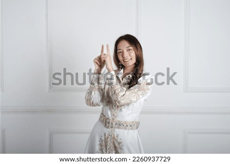 Asian girl pointing to empty space with the hand and fingers. Female wearing floral dress. 