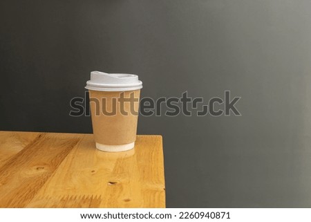 Paper coffee cup on wooden table, gray background