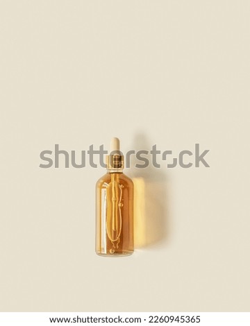 Liquid product packaging in glass bottle on pastel beige background and  beautiful shadow. Hyaluronic or polyglutamic acid oil cosmetic mock up. Facial cosmetics, minimal aesthetic trend, top view Royalty-Free Stock Photo #2260945365