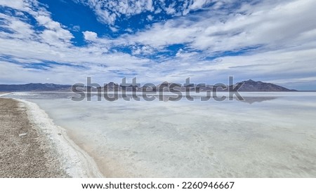 Panoramic view of beautiful mountains reflecting in lake of Bonneville Salt Flats, Wendover, Western Utah, USA, America. Looking at summits of Silver Island Mountain range. West of Great Salt Lake Royalty-Free Stock Photo #2260946667