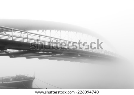 Black and white photo of a steel bridge over a river in fog, Cracow, Poland
