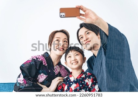 Asian family taking a selfie with a smart phone while wearing a yukata.