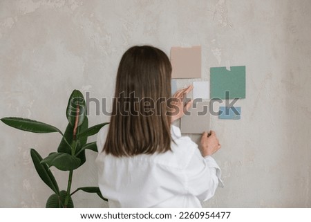 Woman taping colour paper card mockups to a wall. Mood board ideas template.