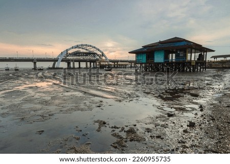Low Tide Foreshore at Sunrise with Orange Skies. Wet beach sand texture after low tide. At Kenjeran Beach, Indonesia.