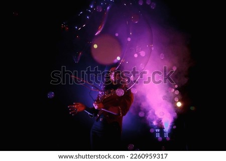 Female magician illusionist circus showing soap bubbles show at black background. Woman actress in theatrical clothes with stylish hat in stage costume. Concept of theatre performance. Copy space Royalty-Free Stock Photo #2260959317