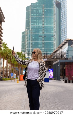 Young woman tourist laughing and taking selfie photo in Dubai Marina in United Arab Emirates. Female traveler and photographer takes picture for her blog.Young happy tourist making selfie.