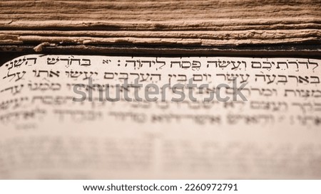 Page of old worn shabby jewish book Torah. Selective focus on snippet Hebrew Bible text that translates in english: offer the Passover sacrifice to Jehovah. Korban Pesach. Closeup Royalty-Free Stock Photo #2260972791