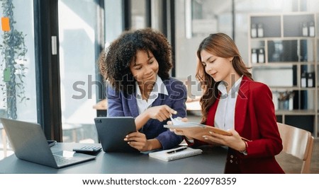 Two Asian businesswoman discuss investment project working and planning strategy with tablet laptop computer in modern office. Royalty-Free Stock Photo #2260978359