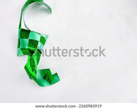 Ketupat or rice dumpling decoration made from green plastic ribbon, isolated on white background
