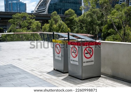 no smoking sign on the side of bins located outdoor of building in city
