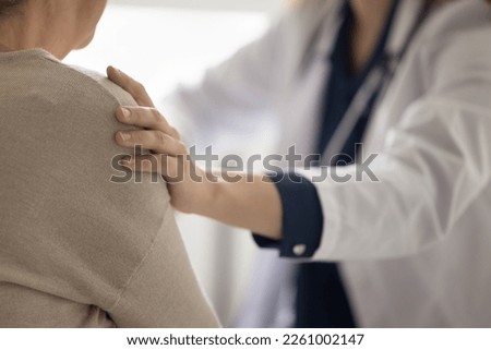 Hand of geriatrician doctor touching shoulder of elderly patient woman, giving empathy, comfort, psychological support, assistance, explaining serious diagnosis of illness. Close up cropped shot Royalty-Free Stock Photo #2261002147