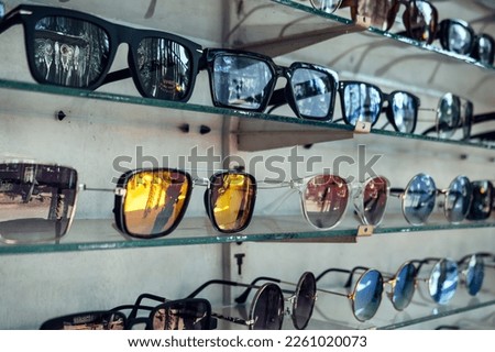 A showcase with a large number of fashionable sunglasses of different shapes. Background for traveling to sunny countries.