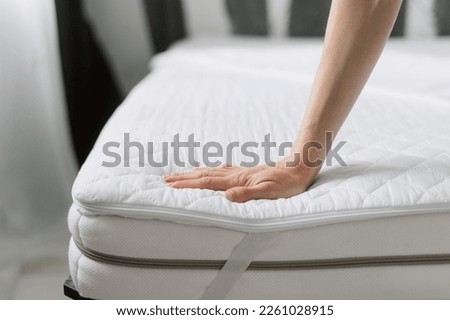 cropped shot of female hands choosing orthopedic memory foam mattress with topper and elastic band on corners on bed at store, protection surface, comfort sleeping concept Royalty-Free Stock Photo #2261028915
