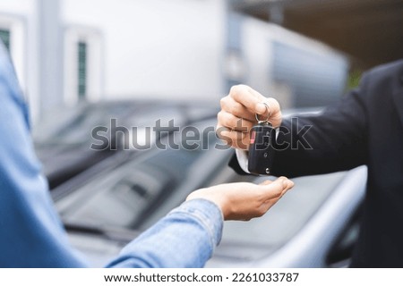 Business car rental, sell or buy service, dealership hand of agent dealer, sale man giving auto key of vehicle to customer renter, buyer young woman receiving, client or tenant, transfer automobile. Royalty-Free Stock Photo #2261033787