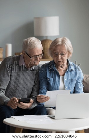 Serious senior wife showing financial paper document to older husband. Elder retired couple doing domestic accounting paperwork together, calculating expenses, budget Royalty-Free Stock Photo #2261034845