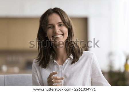 Home portrait of happy beautiful young woman holding transparent glass, drinking fresh natural clear water, keeping healthy hydration, taking care of nutrition, active lifestyle, wellness