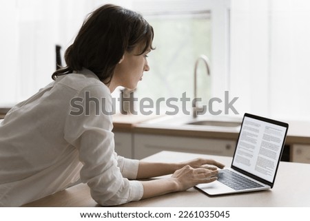 Focused young woman typing on laptop, reading text on screen, monitor. Serious female student, author, blogger creating, editing online article, working on research study