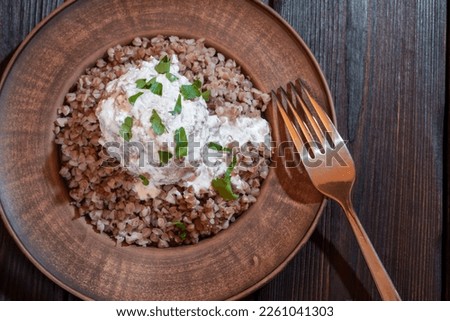 Meatball poured with cream sauce on the background of buckwheat in a plate. Background picture.