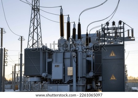 High-voltage transformer substation in winter at dawn. High voltage equipment. Energy transfer technology. Royalty-Free Stock Photo #2261065097