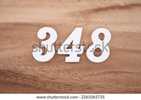 White number 348 on a brown and light brown wooden background.