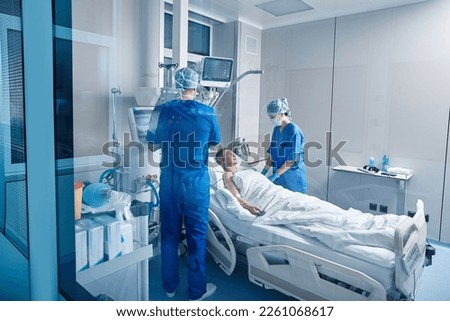Nurses in intensive care unit of hospital checking vitals of hospitalized female patient. ICU Royalty-Free Stock Photo #2261068617