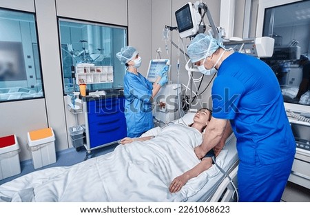 Staff nurses attending to patient in adult intensive care unit. ICU Royalty-Free Stock Photo #2261068623