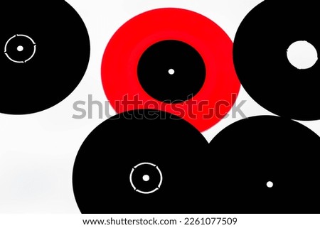 Five vinyl records,one red and four black against a white background.