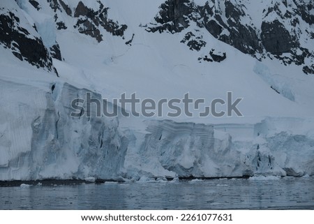 glacier iceberg formations with cracks snow ice in antarctica in ocean sea landscape on a clear blue sky cold with the ice having lines and unique natural sculptures