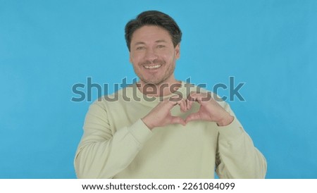 Handsome Young Man with Heart by Hands on Blue Background
