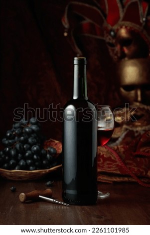 Still life with red wine, grapes, and vintage carnival masks.