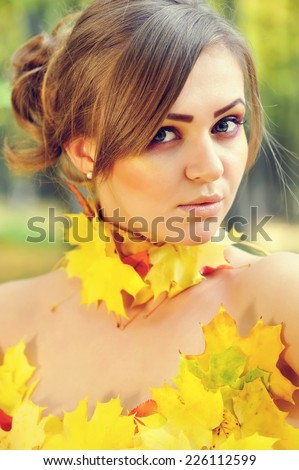 Portrait of a beautiful young woman in autumn leaves