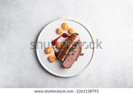 Roast duck breast with carrot cream and berry sauce on a white background, top view