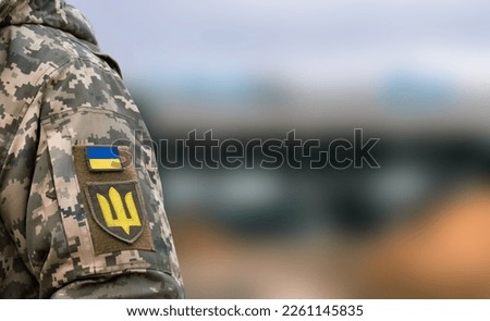 Ukrainian soldier in the army and flag, coat of arms with a golden trident on a military uniform background. Armed Forces of Ukraine. Royalty-Free Stock Photo #2261145835