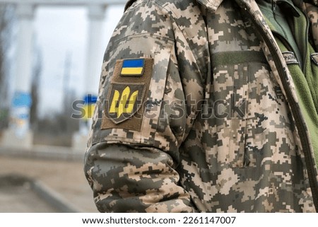 Ukrainian soldier in the army and flag, coat of arms with a golden trident on a military uniform background. Armed Forces of Ukraine.