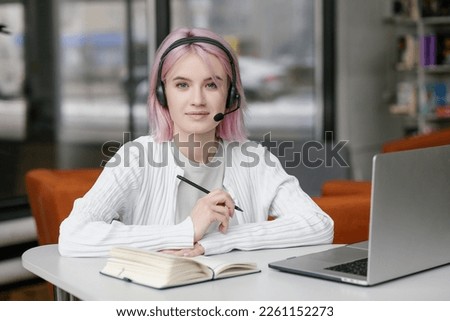 Portrait of young beautiful woman, business woman smiling and looking at camera, receptionist using headset for video call. Young woman employee customer support services in headset