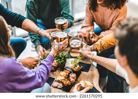 Group of friends cheering beer glasses at brewery pub patio, Happy young people toasting and having fun enjoying at restaurant bar sitting at table-Beverage Life Style concept with guys and girl
