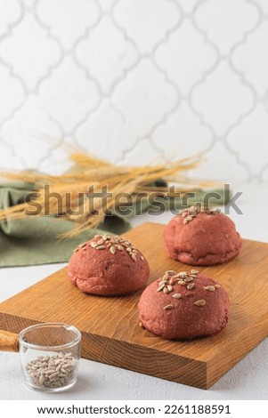Rye and wheat flour bread buns with beetroot puree and sunflower seeds on a wooden board on a light concrete background. Baking bread with the addition of vegetable puree. Scandinavian cuisine