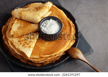 Stack of russian thin pancakes blini with fresh sour cream