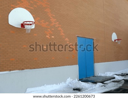 an outdoor basketball hoop on a brick wall in winter