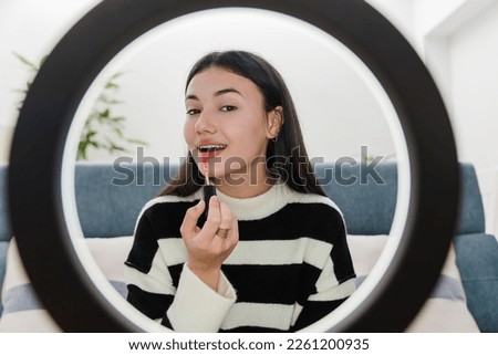 Close up of brunette girl beauty blogger or influencer woman using red velvet color lipstick and talking to followers channel while recording live video with circle ring light