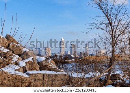 Views of Clevelands skyline beyond boulders and shrubs along the wintery shoreline of Lake Erie at Edgewater Park in Cleveland, Ohio.  